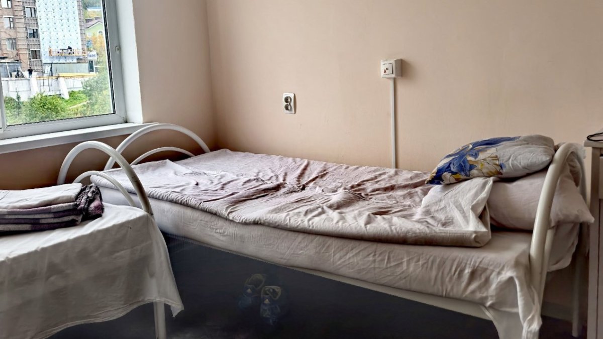 Кровать застеленная в палате больницы на фоне окна летом.