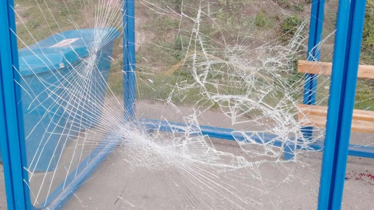 Разбитое стекло остановки общественного транспорта летом в городе.