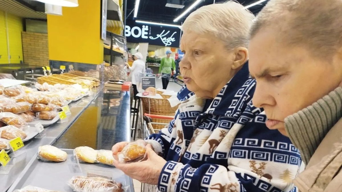 Две пенсионерки стоят у прилавка с пирожками.