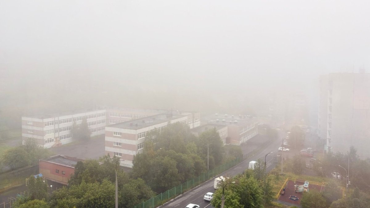 Сильный туман над жилыми домами в городе летом.