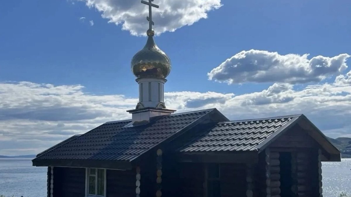 Деревянный храм с позолоченным куплом на фоне моря летом.