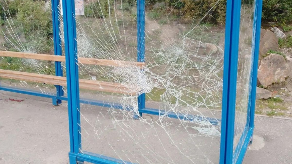Разбитое стекло остановки общественного транспорта.