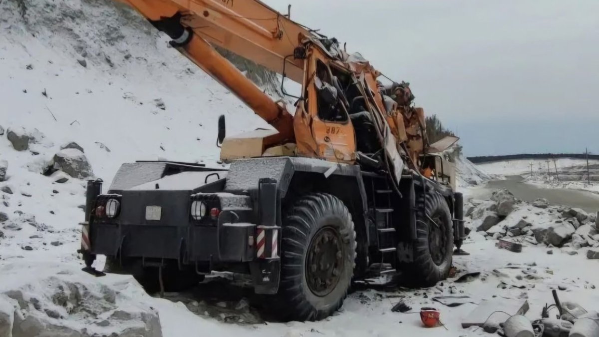 Зимой стоит автокран с мятой кабиной водителя.
