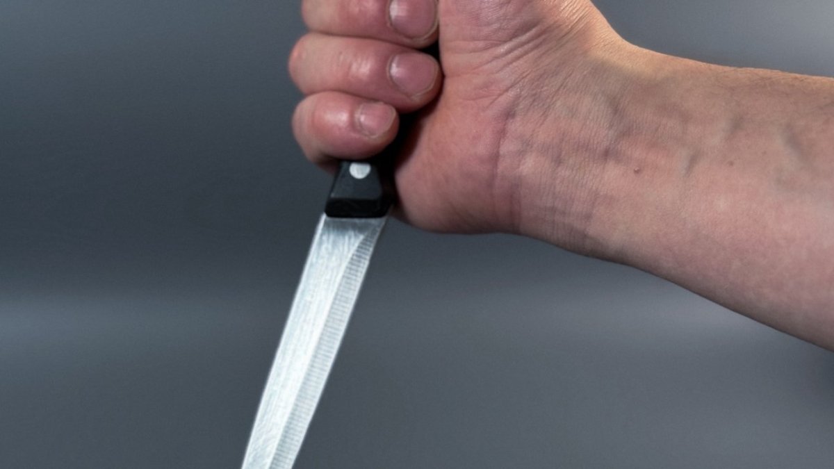 Мужская рука держит большой кухонный нож.
