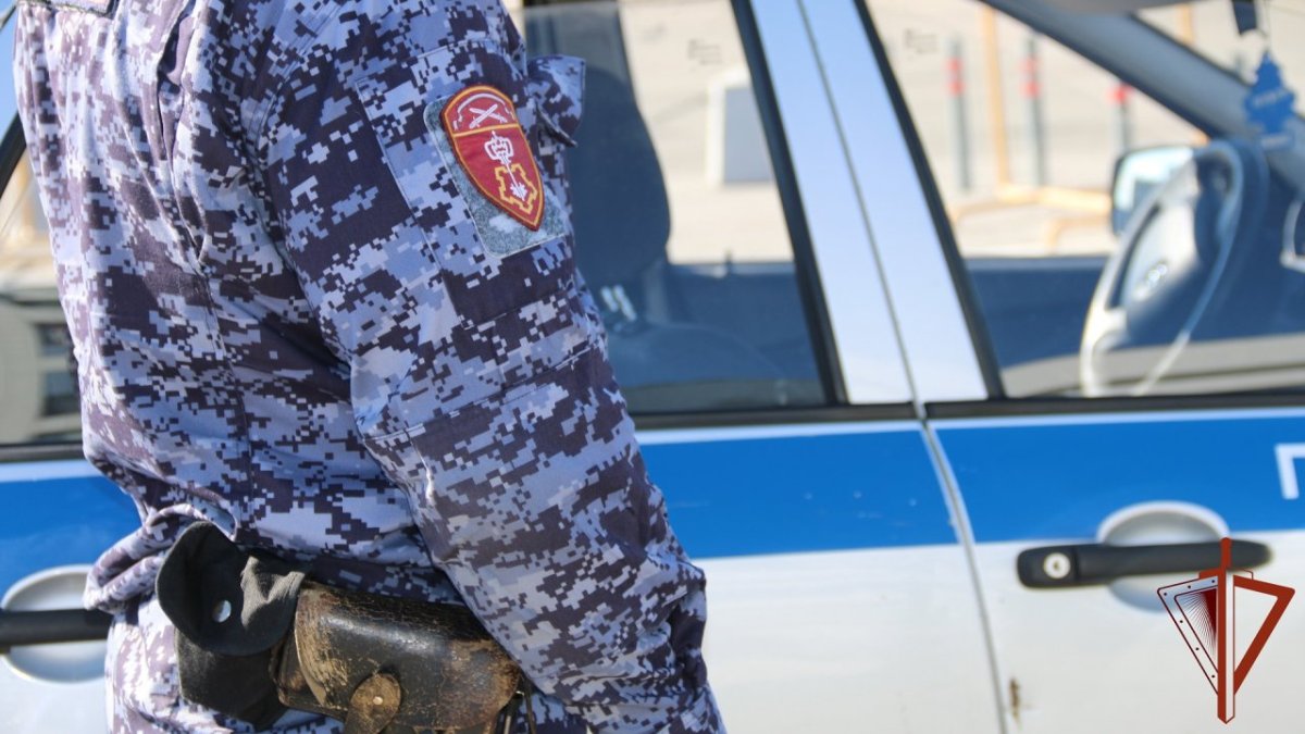 Сотрудник Росгвардии стоит в форме возле служебной машины.