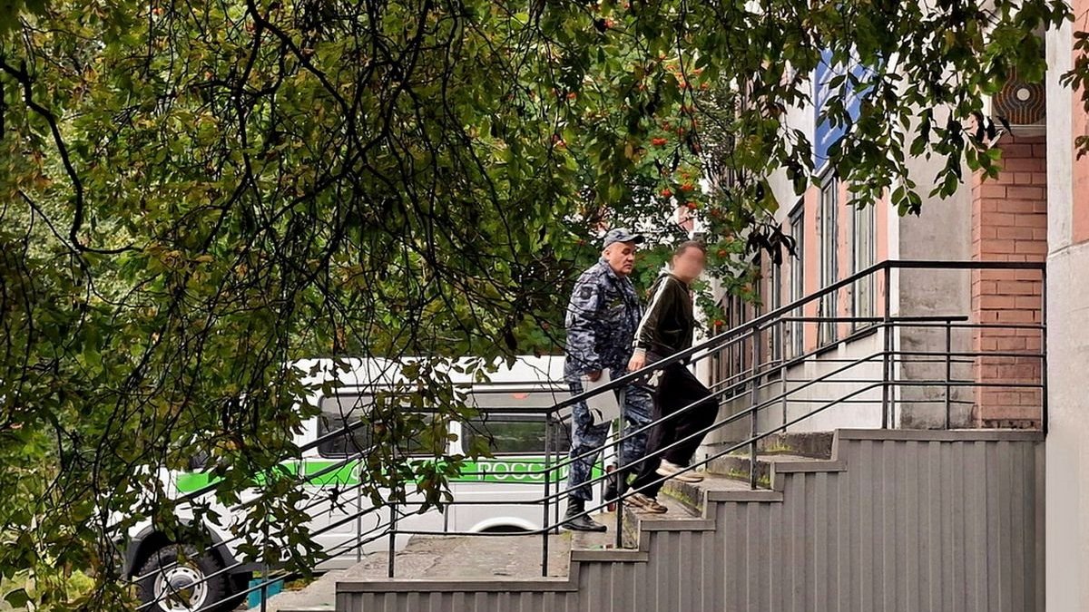 Судебный пристав ведет женщину по лестнице в здании.