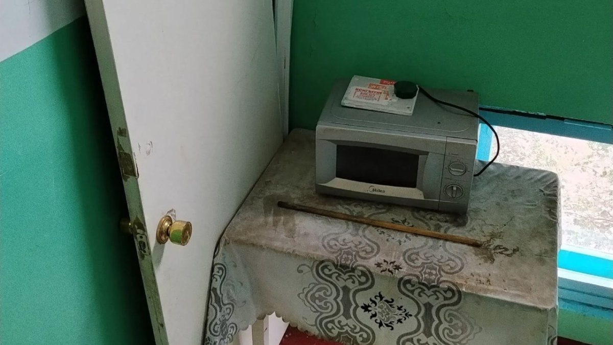 В подъезде дома стоят стол, дверь и микроволновая печь.
