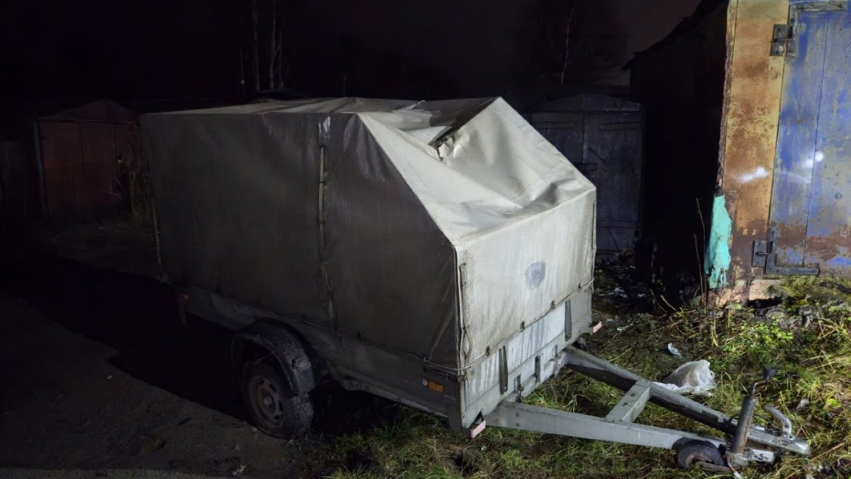 Стоит автомобильный прицеп с вмятиной на чехле.