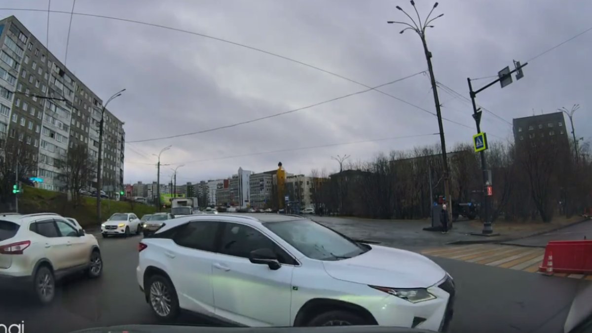 Машина белого цвета стоит на дороге поздней осенью в городе.