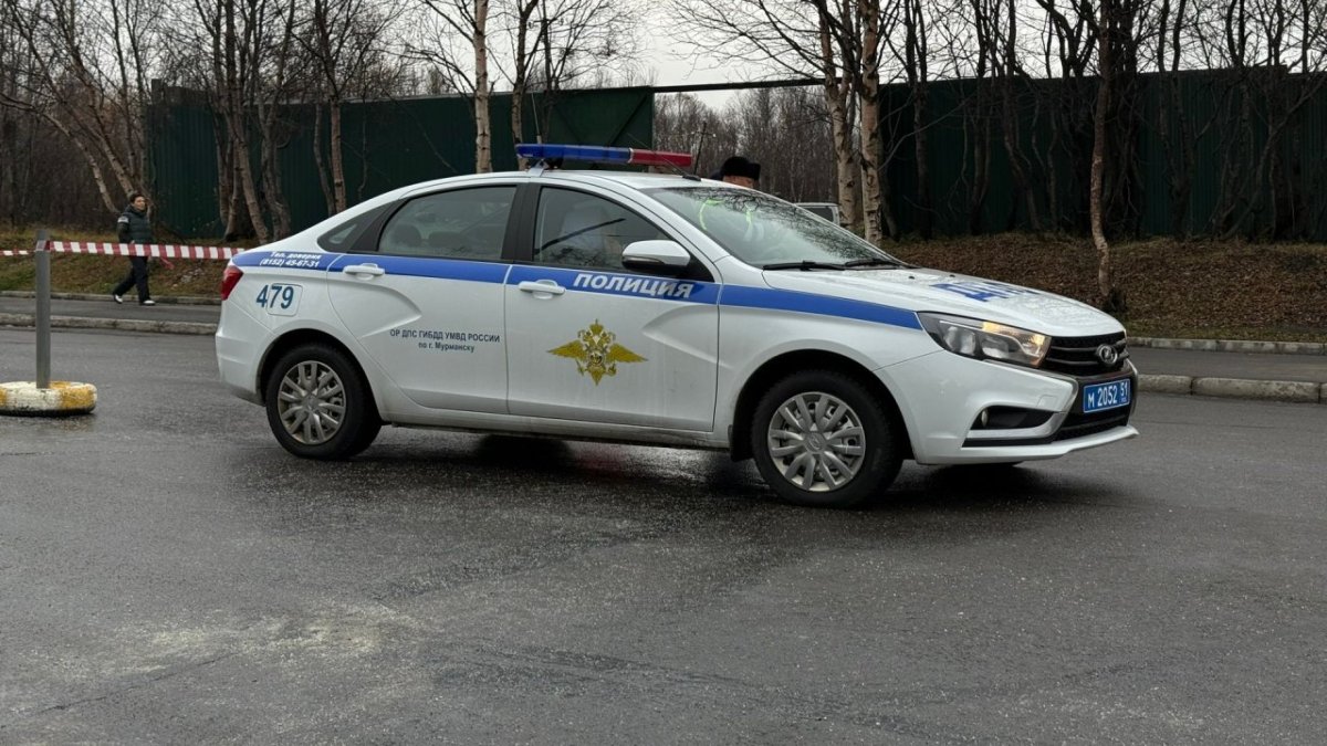 Машина полицейских стоит на дороге рядом с оградительной лентой осенью.