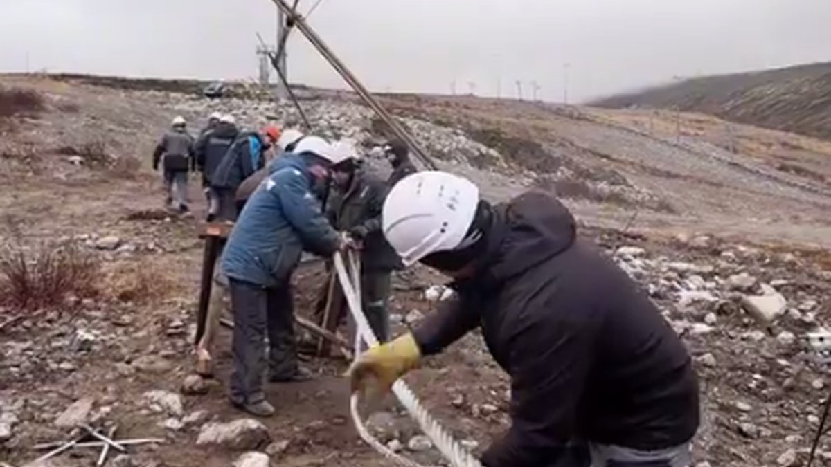 Сотрудники горнолыжного комплекса ремонтируют канат подъемника на горе.