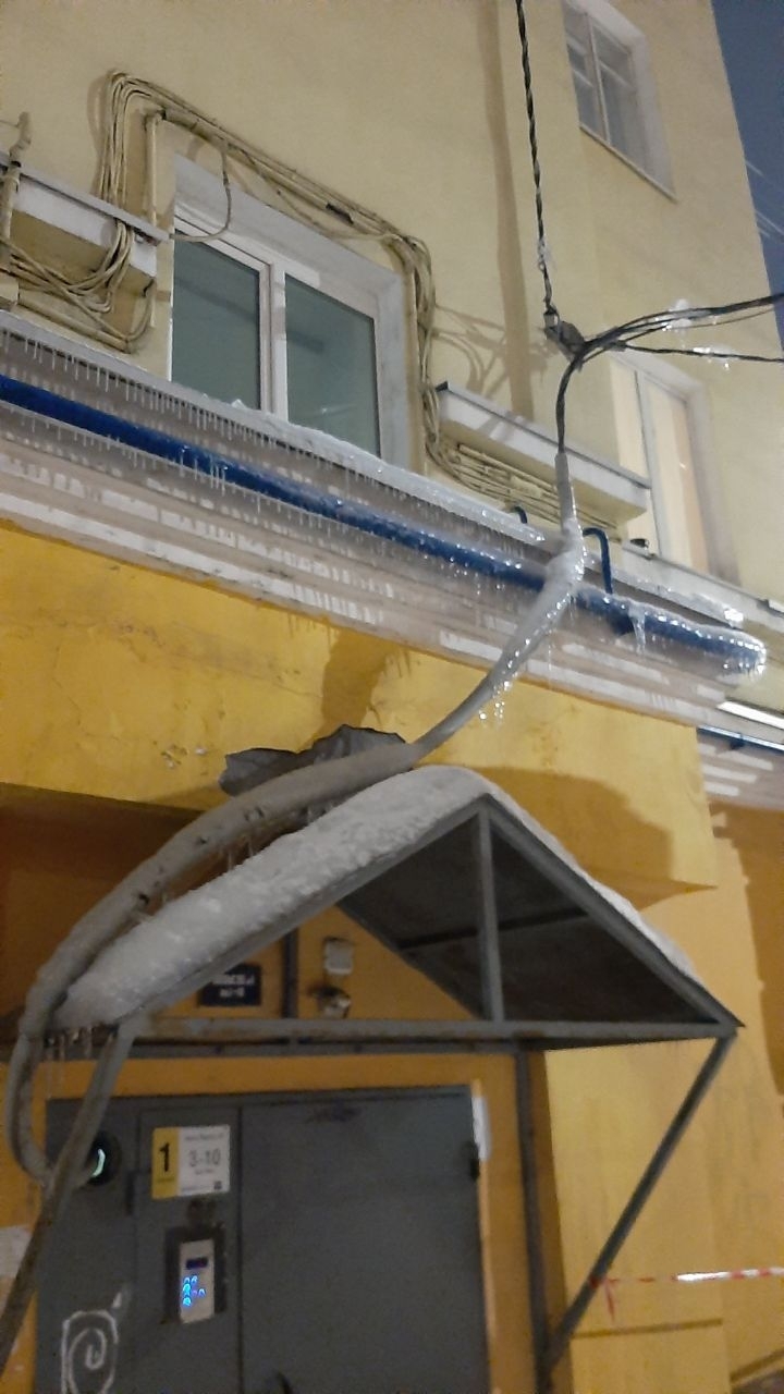 В Мурманске над подъездом дома газовую трубу и электрокабель покрыл толстый слой льда