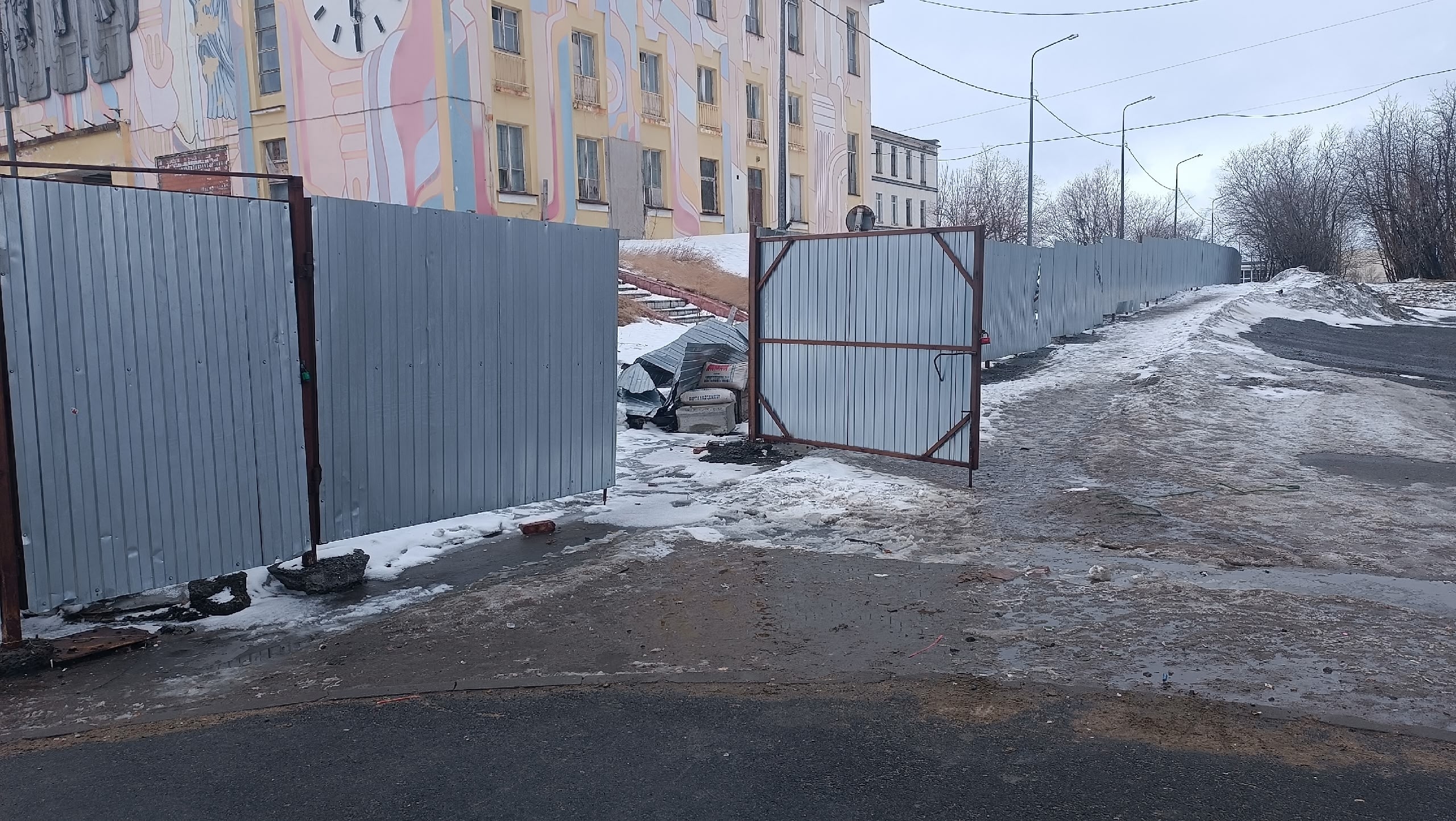 «Ждёте, пока кто-нибудь получит травму?»: в Никеле от забора ДК отлетают куски обшивки прямо в пешеходов